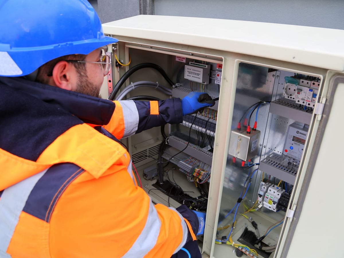 Technicien en tenue de protection intervenant sur une armoire électrique ouverte
